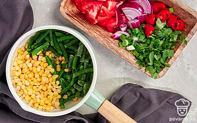 Подготовьте овощи для соуса. Стручковую фасоль и зерна кукурузы отварите в течение 10 минут и остудите. Помидоры, красный лук, чеснок и перец чили произвольно крупно порежьте. Кинзу и зеленый лук мелко порежьте. Все эти ингредиенты поместите в чашу блендера.