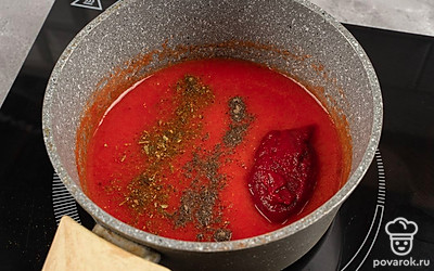 Когда паста нагреется, высыпьте в нее соль, сахар и хмели-сунели. Хорошо перемешайте, чтобы сыпучие ингредиенты растворились. Вмешайте аджику. Оставьте кастрюлю на плите, пока паста не загустеет.