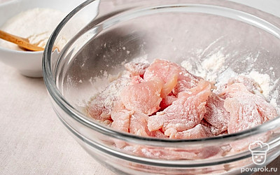 Нарежьте куриное филе на небольшие кусочки. Обваляйте курицу в муке.
