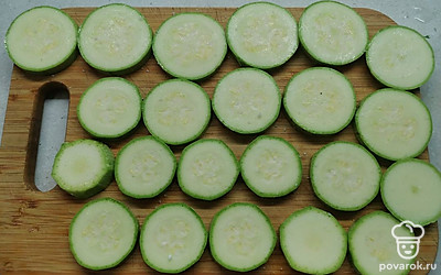 Кабачок нарежьте на кружочки толщиной около 1 сантиметра. Если кабачок молодой, кожуру можно не снимать. Слегка посолите с двух сторон. 