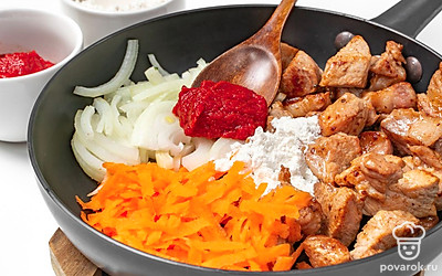 Обжарьте продукты. Свинину выложите на сковороду с раскаленным маслом, обжарьте до корочки. Всыпьте измельченные овощи и пожарьте вместе с мясом несколько минут на среднем огне. Добавьте томатную пасту и муку, перемешайте.