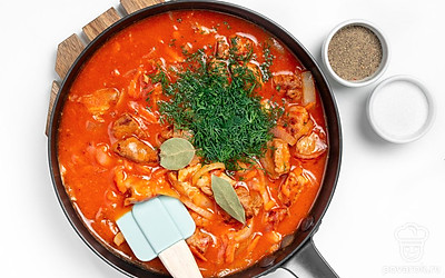 Завершите приготовление. В скороводу влейте 0,5 стакана горячей воды. Убавьте огонь до минимума. Всыпьте соль, перец. Добавьте лавровый лист и рубленую зелень. Накройте крышкой и тушите 30 минут. Выключите огонь и дайте настояться 10 минут.