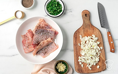 Нарежьте рыбу на небольшие ломтики. Положите налима в миску, посолите и поперчите. Мелко покрошите репчатый лук и петрушку. Пропустите чеснок через пресс.