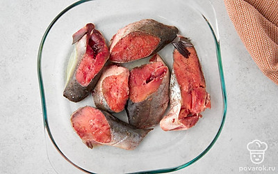 Посолите и поперчите куски кеты. Вотрите специи в рыбу руками. Смажьте форму для запекания небольшим количеством масла. Выложите стейки в форму.