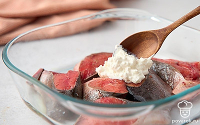 Включите духовку на разогрев до 180°C. Натрите сыр. Смешайте со сметаной. Намажьте сырно-сметанную смесь поверх кусочков рыбы. Отправьте форму с рыбой в духовку на 20 минут до образования румяной сырной корочки.