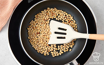 Обжарьте очищенные кедровые орехи на сухой сковороде, постоянно помешивая, до появления яркого орехового аромата. Переложите орехи в чашу блендера.