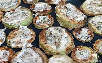 Смажьте майонезом кабачки. Помидор нарежьте кубиком и выложите сверху.