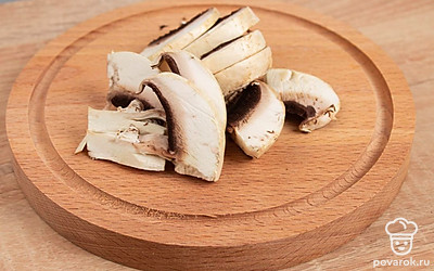 В воде сварите лапшу. Как будет готова, слейте жидкость. Шампиньоны разрежьте пополам, а затем на небольшие пластины.