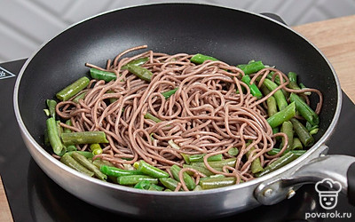 Влейте на сковороду вторую часть соевого соуса и вторую часть растительного масла. Добавьте отваренную лапшу, зеленую фасоль и прогрейте ее в течении 2-3 минут. По желанию добавьте еще зубчик чеснока, нарезанный тонкими слайсами.