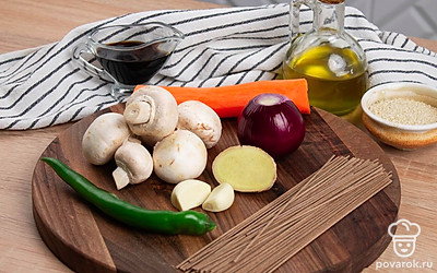 Сварите собу в подсоленой воде. Время варки уточните на упаковке. Шампиньоны промойте водой и быстро обсушите, чтобы они не впитали лишнюю влагу. Морковь, чеснок, корень имбиря и лук очистите.