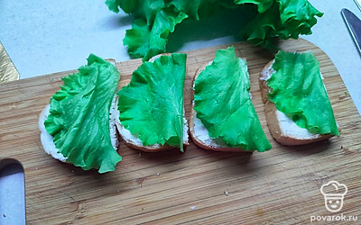 На каждый ломтик хлеба положите лист салата. 