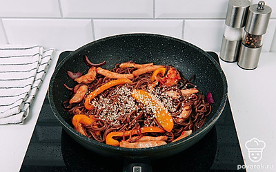 Готовую лапшу добавьте к овощам и курице. Перемешайте, посыпьте кунжутом.