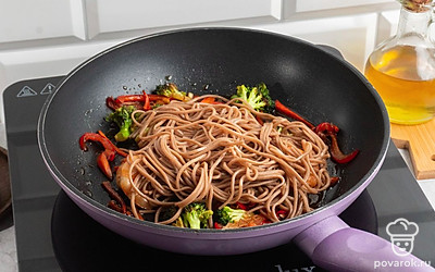 Добавьте лапшу на сковородку, залейте блюдо соевым соусом, выжмите лимонный сок на лапшу с овощами и креветкам, готовьте на среднем огне в течении еще 10-15 минут.