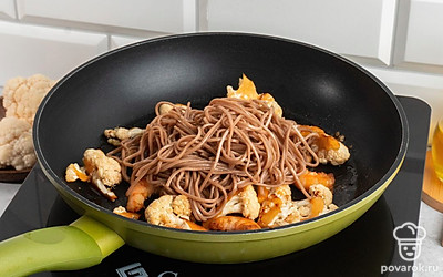 Добавьте лапшу на сковородку, залейте блюдо соевым соусом, готовьте на среднем огне в течении еще 10-15 минут.