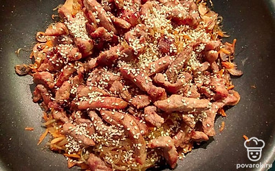 К хорошо притушенным овощам и рисовой лапше добавьте мясо, влейте все остатки кунжутного масла и тщательно перемешайте. Присыпьте блюдо кунжутом, и выключайте огонь.