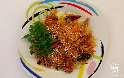 Подавайте фунчозу с шампиньонами и свининой на красивой тарелке, украшенную веточкой зелени.