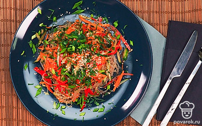 Подавайте салат из фунчозы, болгарского перца и моркови в красивой тарелке, посыпав любой зеленью и кунжутными семечками.