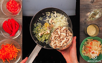 Приготовьте грибную зажарку. Во второй сковороде разогрейте масло. Выложите в него лук, чеснок, сельдерей, грибы. Обжаривайте до испарения жидкости 5-7 минут. Затем добавьте морковь. Оставьте томиться около 2 минут. Добавьте измельченную мякоть помидора, болгарский перец. Перемешайте и готовьте 7 минут.