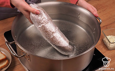 Приготовьте колбасу. Налейте в широкую кастрюлю воду, влейте уксус и всыпьте соль. Поставьте кастрюлю на огонь и дождитесь, пока вода закипит. Погрузите колбасу в кипяток. Вода должна покрыть ее полностью. Накройте кастрюлю крышкой, варите 60 минут. Готовую колбасу выложите на блюдо и дайте остыть.