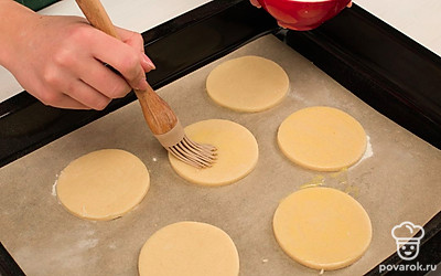 Выложите заготовки на противень, смажьте взбитым яйцом и запекайте в разогретой духовке в течение 12 минут.