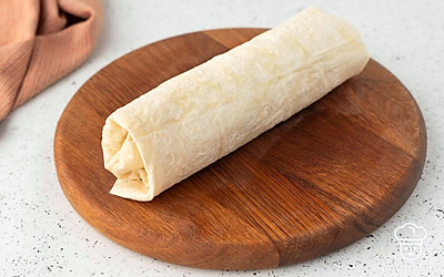 Накройте начинку пустой половиной лаваша. Подверните внутрь один из краев, чтобы овощи при сворачивании не выпали. Сверните лаваш в тугой рулет. Разрежьте поперек на две части, чтобы начинка красиво смотрелась в разрезе.