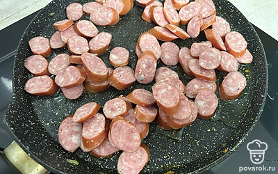 Охотничьи колбаски нарежьте кружками. Обжаривайте в течение 5-7 минут.