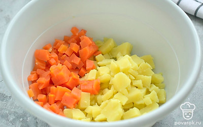 Вареный картофель и вареную морковь нарежьте для салата маленькими кубиками. Переложите нарезку в салатник.