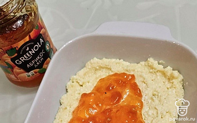 Смажьте форму для запекания небольшим количеством подсолнечного масла. Разделите тесто на 2 части. Выложите одну часть равномерно на дно формы. Добавьте джем и распределите его тонким слоем поверх теста.