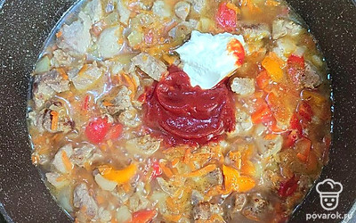 Добавьте воду, томатнуй соус, сметану. Посолите, добавьте специи, тушите все вместе 20 минут. 