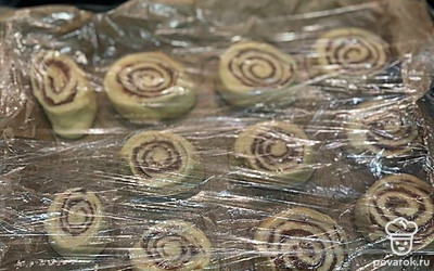 Противень застелите пергаментной бумагой. Выложите булочки. Накройте пищевой пленкой и поставьте в теплое место на 30 минут. 