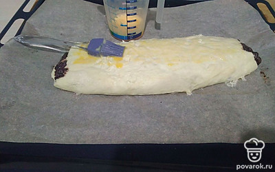 Сверните тесто в рулет. Край закрепите, смачивая тесто водой. Выложите рулет швом вниз на противень, застеленный пергаментом. Для румяной корочки смажьте рулет желтком с молоком.