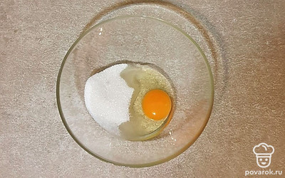 В глубокую миску вбейте куриное яйцо. Всыпьте сахар и взбейте около 2 минут. В этом рецепте можете использовать обычный венчик и взбивать им.