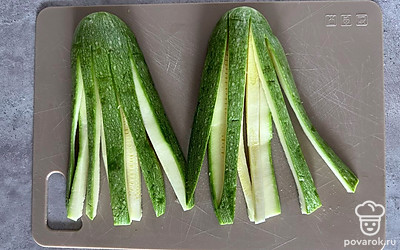 Кабачок промойте, разрежьте вдоль на 2 части. Затем каждую половину еще раз разрежьте вдоль, не дорезая до основания. Каждую половинку разрежьте на тонкие продольные полоски.