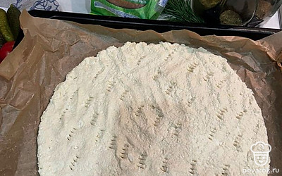 Мокрыми руками выложите тесто на застеленный пергаментом противень и сформируйте основу для пиццы. Наколите вилочкой тесто и отправьте в разогретую до 180 градусов духовку на 15 минут. 