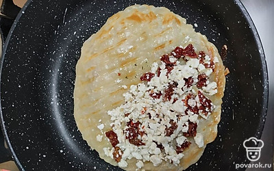На сухую разогретую сковороду положите замороженную лепешку. Обжарьте ее с одной стороны. Переверните и выложите на один край начинку.