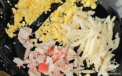 Желток разломайте вилкой, натрите сыр и крабовые палочки.