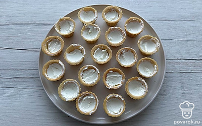 Пока креветки остывают, заполните тарталетки творожным сыром наполовину.