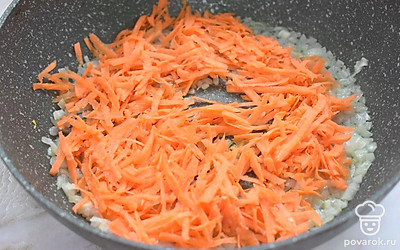 Параллельно займитесь остальными ингредиентами. Прогрейте в сковороде растительное масло. Выложите в масло нарезанный мелко лук. Жарьте лук 2-3 минуты. Затем добавьте к луку натертую морковку. Перемешайте ингредиенты и продолжайте обжаривать 3 минуты. 