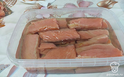 Возьмите пластмассовую емкость, чтобы поместилась рыба. Налейте масло и выложите рыбу. Поперчите, добавьте лавровый лист и кусочки лимона.