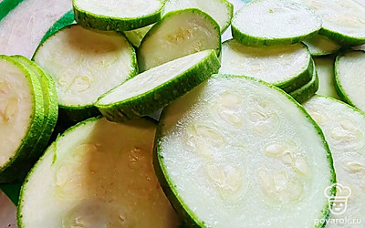 Возьмите молодой кабачок. Нарежьте его пластинками толщиной 0,5 сантиметров. Переложите их в большую емкость и посыпьте солью, чтобы выделился сок.