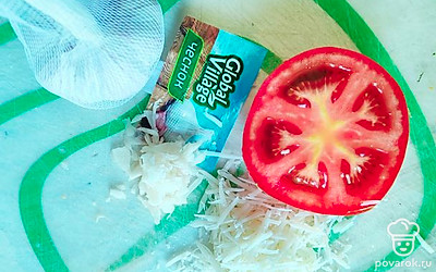 Зубчик чеснока измельчите ножом, сыр натрите на мелкой терке. Помидор нарежьте произвольно.