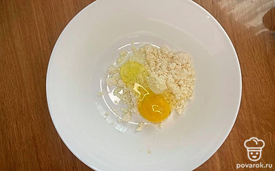 В чашу положите творог. Вбейте яйцо.