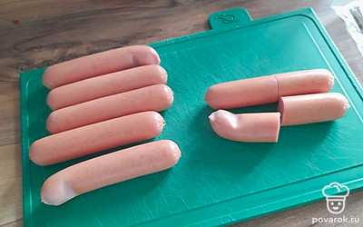 Возьмите сосиски, почистите их и разрежьте пополам.