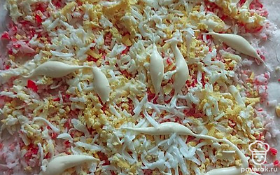 Выложите яйца поверх крабовых палочек. Приправьте майонезом. 