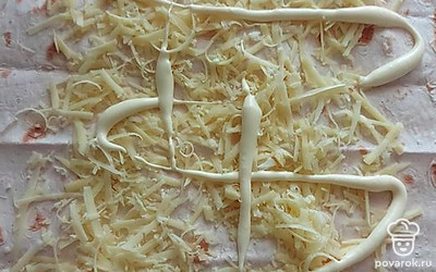 Сверху положите лаваш. Натрите сыр на крупной терке, чеснок — на мелкой терке. Выложите все на лаваш. Тоже смажьте майонезом.