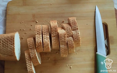 Подсушенный багет нарежьте на порционные кусочки толщиной в 1 сантиметр.