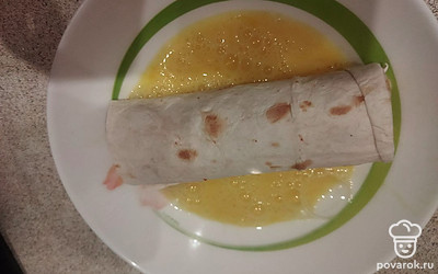 Сверните лаваш с сосиской и сыром в рулет. Обмакните его в взбитое куриное яйцо.