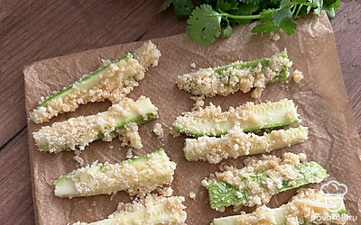 Обмакните дольки кабачка в яйцо, затем обваляйте в смеси из сухарей и пармезана, выложите на пергамент. Выпекайте 20 минут при 180 градусах.