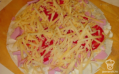 Сыр натрите на терке, выложите на томаты и колбасу. Сложите лаваш пополам.