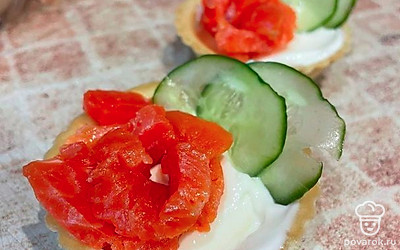 Огурец нарежьте тонкими кусочками, добавьте в тарталетки.